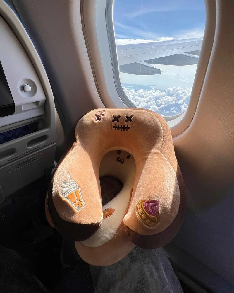 Two Toasty travel pillows beside an airplane window overlooking the clouds.