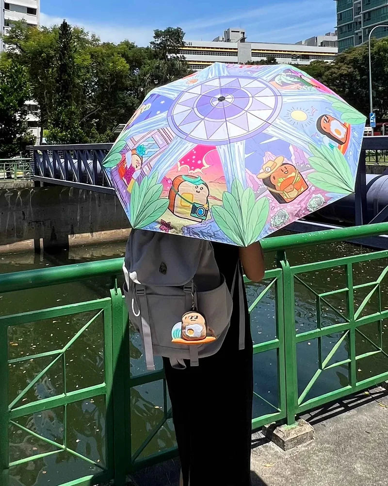 Holiday Toastys umbrella above a grey backpack carrying Surfer Toasty beside a sunny canal.