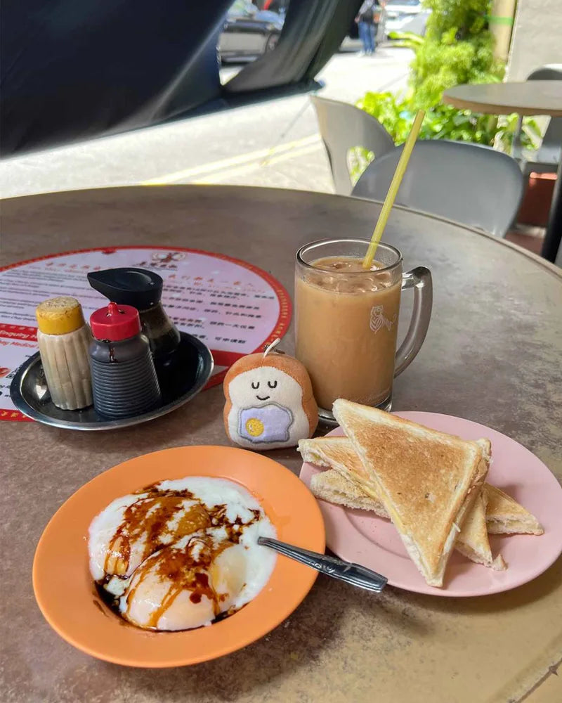 Starter Toasty egg charm beside eggs, toast and an iced drink at a café table.
